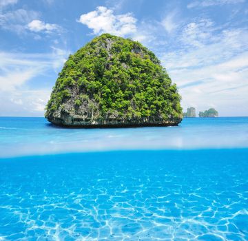 Beautiful uninhabited island in Thailand with white sand bottom underwater and above water split view