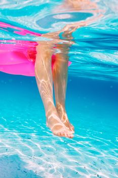 Woman relaxing on inflatable mattress at the beach, view from underwater