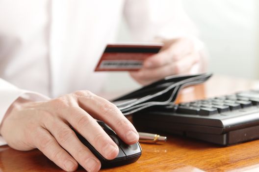 Hands of businessman with a purse and a bank card on the computer keyboard