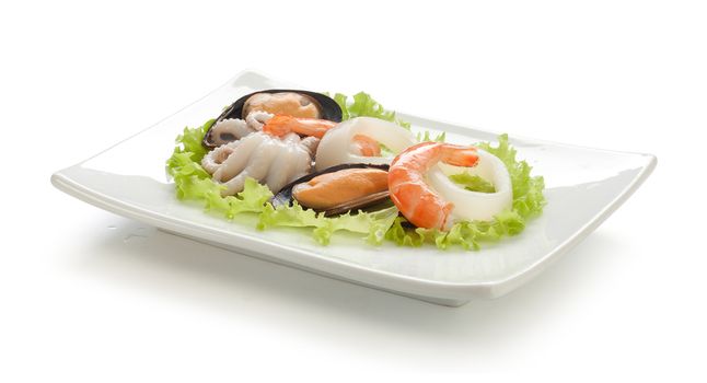 Shrimp's tails, octopus, squid, mussels and green fresh lettuce on the white plate