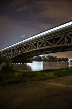 Bridge by night. Old train bridge with lights and dark sky, National Stadium by Vistula river. Illuminated railway bridge in Warsaw, Poland (Europe)