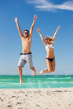 picture of happy couple jumping on the beach.