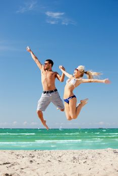 picture of happy couple jumping on the beach (focus on man).