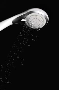 Modern shower head with running water isolated on black background