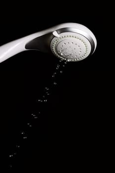 Modern shower head with running water isolated on black background