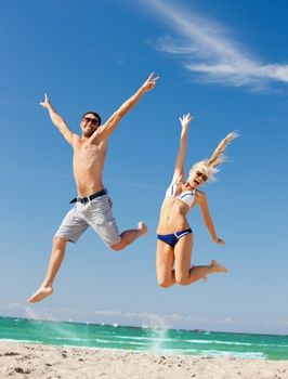 picture of happy couple jumping on the beach (focus on woman)