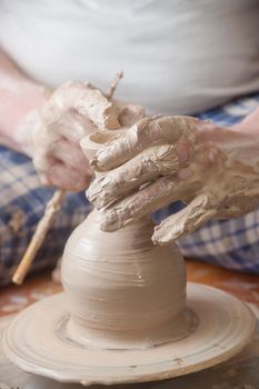 Hands of a potter, creating an earthen jar on the circle