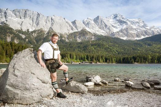 A traditional bavarian man at lake Eibsee with the Zugspitze mountain in the background