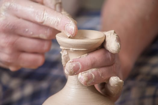 Hands of a potter, creating an earthen jar on the circle