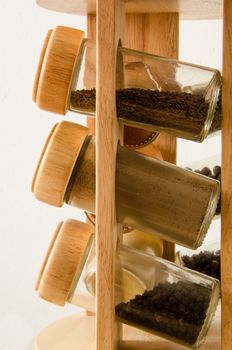 Wooden stand with spices in jars isolated on white background.