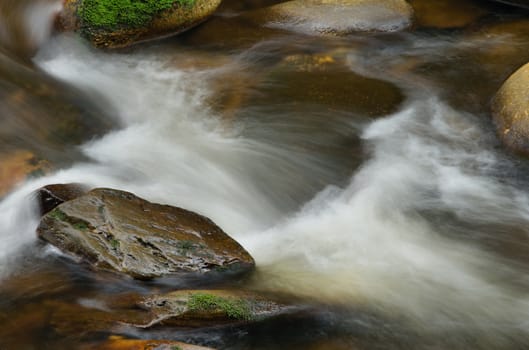 Detail of small beautiful cascade between mossy stones. 