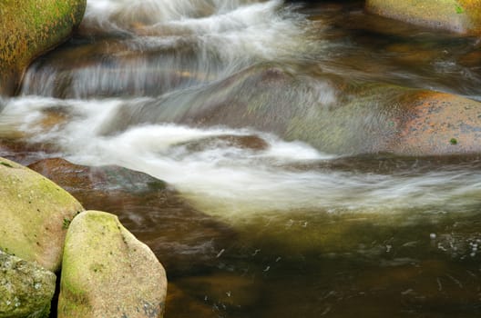 Detail of small beautiful cascade between mossy stones. 