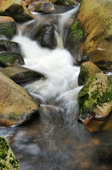 Detail of small beautiful cascade between mossy stones. 