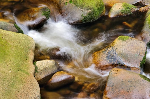 Detail of small beautiful cascade between mossy stones. 