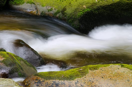 Detail of small beautiful cascade between mossy stones. 