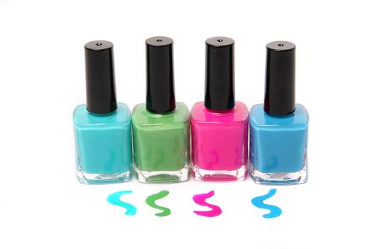 Nail polish bottles and spots in bright spring or summer colors in light blue, pink and green on a white background