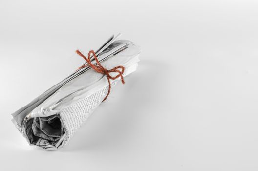 rolled up newspaper focus on red rope on a white background