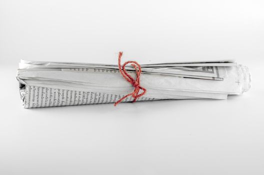 rolled up newspaper focus on red rope on a white background