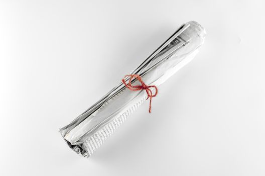 rolled up newspaper focus on red rope on a white background