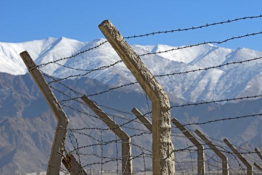 Barbed wire fence in winter with snow mountain background