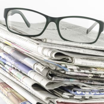 stack of newspaper with glasses on a white background