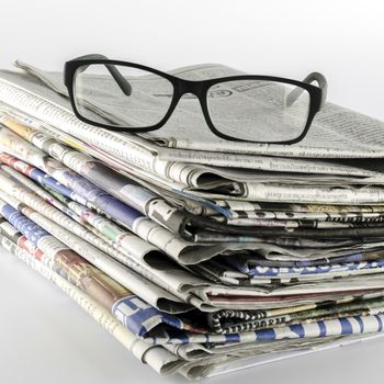 stack of newspaper with glasses on a white background