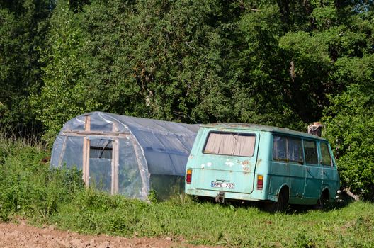 greenhouse and old rustic mini bus in garden meadow