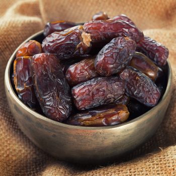 Pile of fresh dried date fruits in metal bowl. Dried date palm fruits or kurma, ramadan food which eaten in fasting month. 