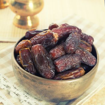 Dried date palm fruits or kurma, ramadan food which eaten in fasting month. Pile of fresh dried date fruits ready to eat in metal bowl.