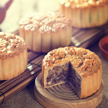 Retro vintage style Chinese mid autumn festival foods. Traditional mooncakes on table setting with teacup. The Chinese words on the mooncakes means assorted fruits nuts, not a logo or trademark.