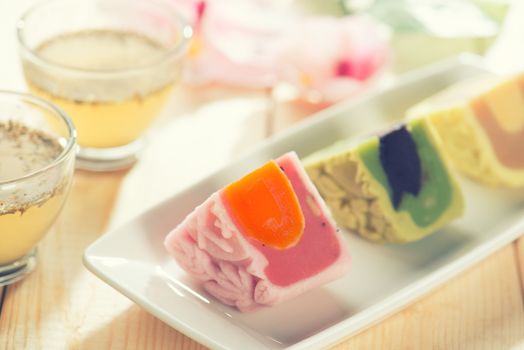 Colorful snow skin mooncakes on white plate with teacup. Chinese mid autumn festival foods. 
