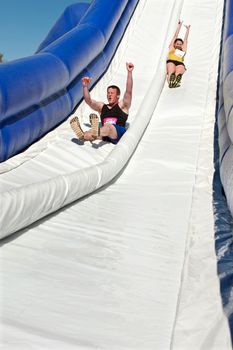 Atlanta, GA, USA - April 5, 2014:  A young man and woman enjoy sliding down a watery slide in the Ridiculous Obstacle Challenge (ROC) 5K race.