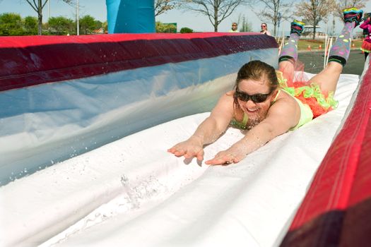 Atlanta, GA USA - April 5, 2014:  A young woman dives onto a wet plastic slide as she makes her way through the obstacles at the Ridiculous Obstacle Challenge (ROC) 5K race.