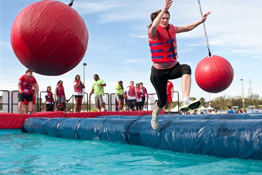 Atlanta, GA USA - April 5, 2014:  A woman begins to slip and fall into the water trying to run through the wrecking balls event, at the Ridiculous Obstacle Challenge (ROC) 5K race.