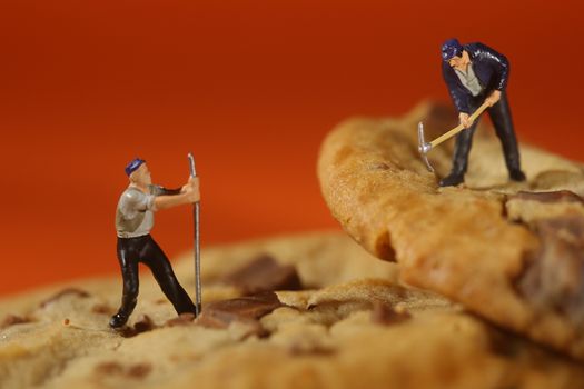 Miniature Plastic People Working on Chocolate Chip Cookies