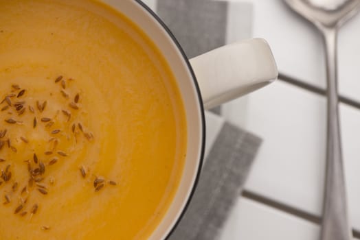 Retro styled mug full of Pumpkin soup with toasted cumin seeds on top