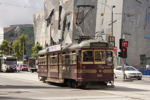 Melbourne, Australia-March 18th 2013: The City Circle tram and cars trundles past Federation Square on Flinders St. The tram route is a free service running around Melbourne's CBD.