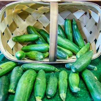 Fresh healthy green zucchini courgettes in basket on the marketplace