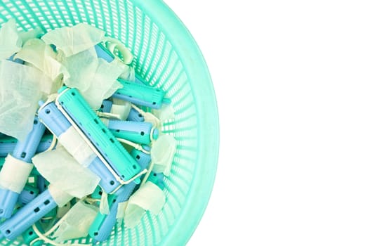 Used blue plastic curler and hair in basket isolated with white background.