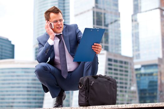 successful businessman talking on the phone on the background of office buildings