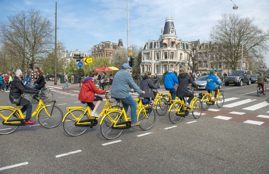 Amsterdam, The Netherlands - April 05, 2014: Torists riding bikes in Amsterdam, Holland. Bicycle rentals are readily available throughout the city. Central Station, Leidseplein and Dam Square are all major rental hubs.