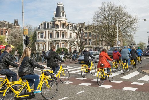 Amsterdam, The Netherlands - April 05, 2014: Torists riding bikes in Amsterdam, Holland. Bicycle rentals are readily available throughout the city. Central Station, Leidseplein and Dam Square are all major rental hubs.