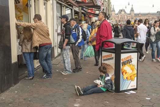 Amsterdam, The Netherlands - April 05, 2014; People eating take away fast food in the street, near central Railway station in Amsterdam