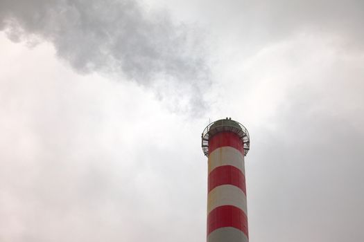 Industrial chimney smoking in the cloudy weather