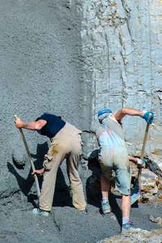 OSTFILDERN-SCHARNHAUSEN, GERMANY - MAY 22, 2014: Two workers are shovelling concrete against the earth walls surrounding a construction site on May, 22, 2014 in Ostfildern-Scharnhausen near Stuttgart, Germany.