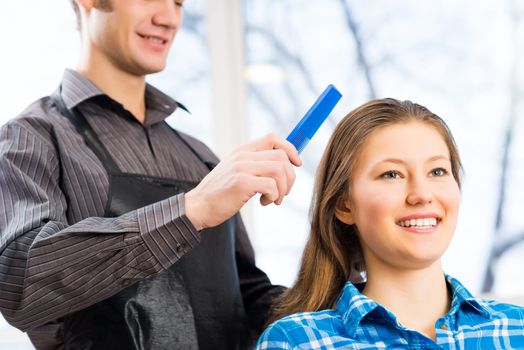 male hairdresser puts woman's hair in a hairdressing salon