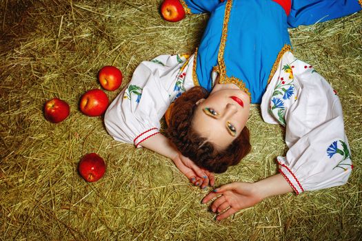 Attractive young girl from Eastern Europe lies on her back on fresh hay
