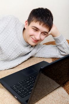 Cheerful Teenager with Laptop on the Sofa at the Home