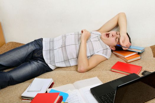 Tired Teenager Yawning on the Sofa with the Books at the Home