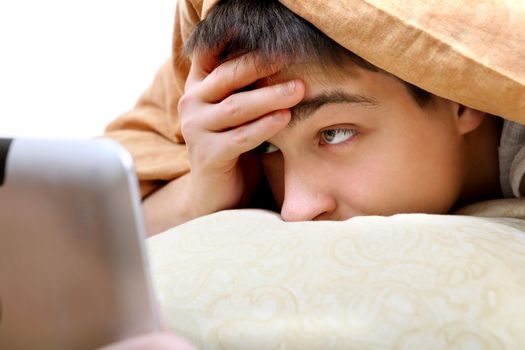 Teenager with Tablet Computer under Blanket at the Home
